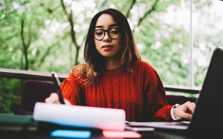 woman using a computer and writing down information about how to budget